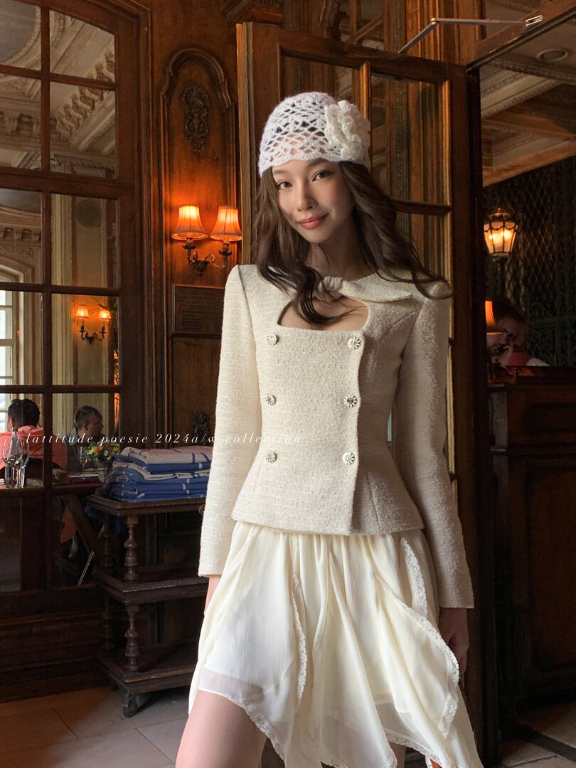 Woman wearing a cream textured dress and matching knit hat in an ornate interior