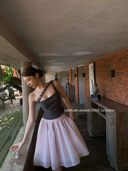 Model wearing a black asymmetrical top with a light pink tulle skirt