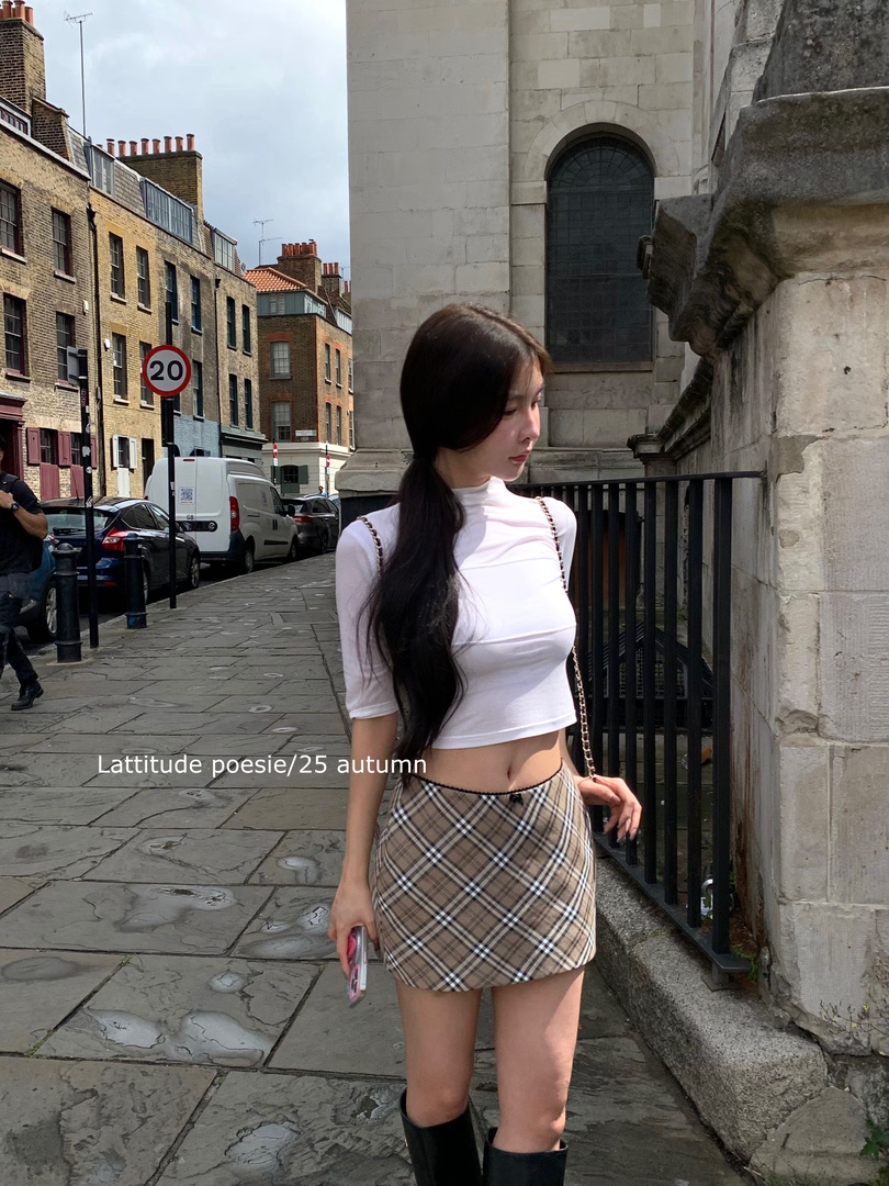 Woman wearing a white fitted top and plaid mini skirt outdoors