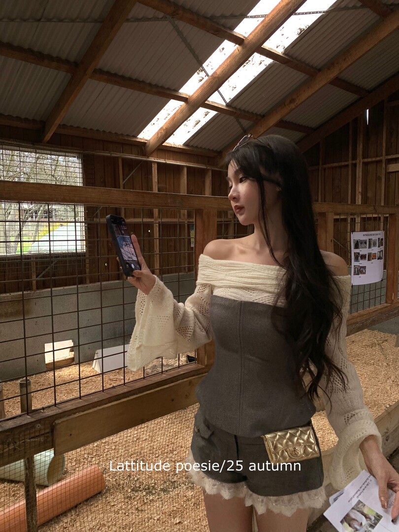 Woman wearing an off-shoulder knit outfit with shorts and a small gold quilted bag