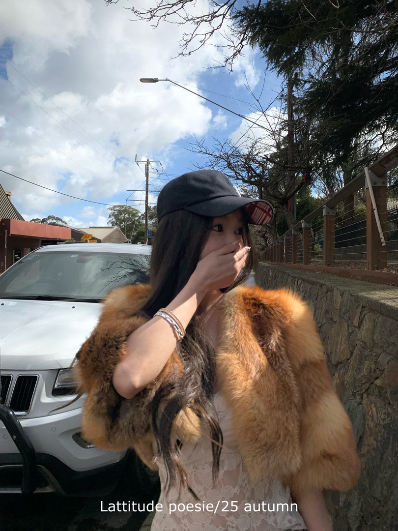 Woman wearing a brown fur stole/coat and black cap outdoors