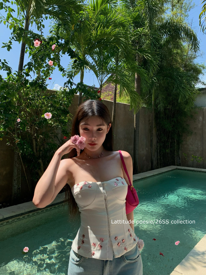 Woman wearing a white floral strapless top by a pool