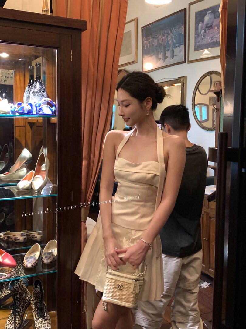Beige halter mini dress worn by a woman in a boutique