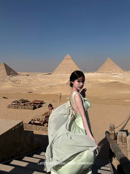 Model wearing a light green flowing dress in a desert landscape