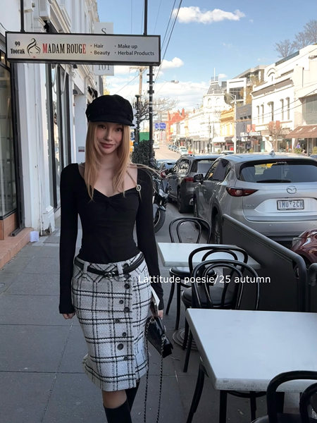 Woman modeling a black top and plaid skirt outfit on a street