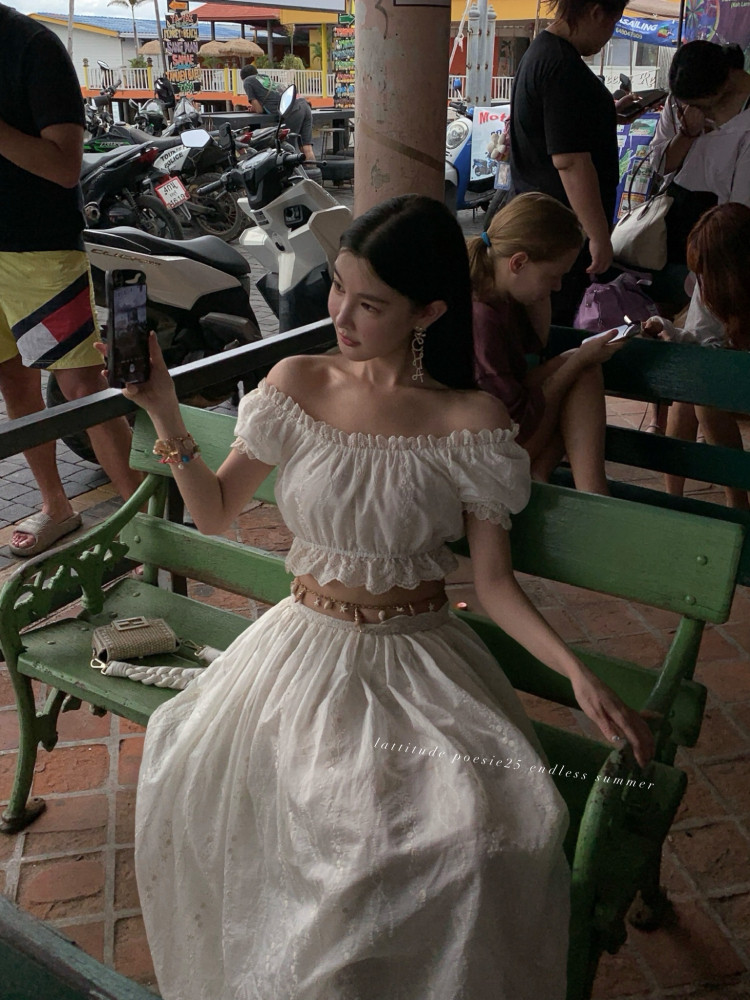 Woman wearing a white off-shoulder crop top and matching long skirt