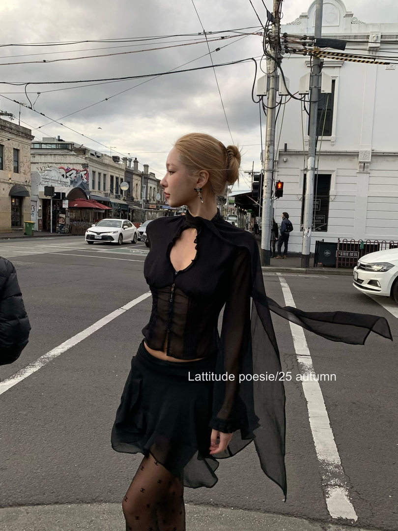 Model wearing a black sheer long-sleeve fashion outfit on a street