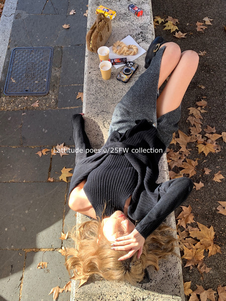 Woman wearing a black knit outfit outdoors on a bench in autumn scenery
