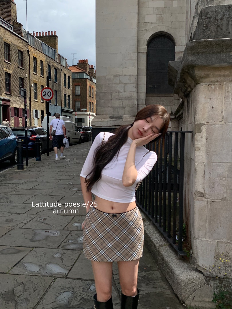 Woman wearing a white cropped top and plaid mini skirt outdoors
