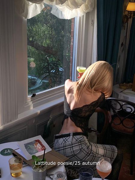 Woman wearing a black lace top and plaid pants seated by a window in a restaurant
