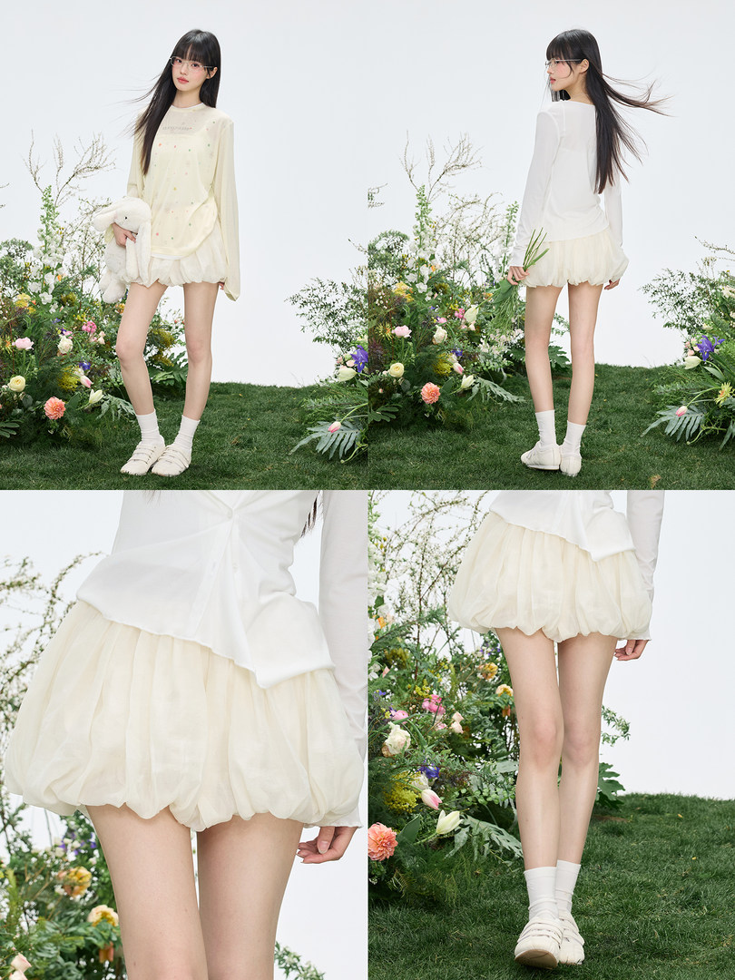 Model wearing a cream long-sleeve top with a light puffed skirt or shorts outfit