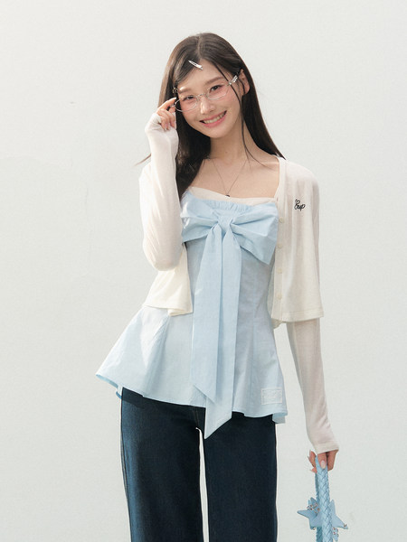 Model wearing a light blue bow-trim camisole with a cream cardigan and dark jeans