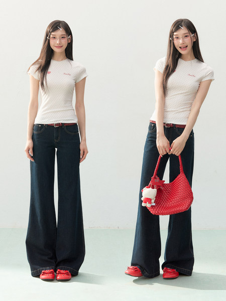 Model wearing a white fitted T-shirt, dark wide-leg jeans, and red shoes with a red handbag