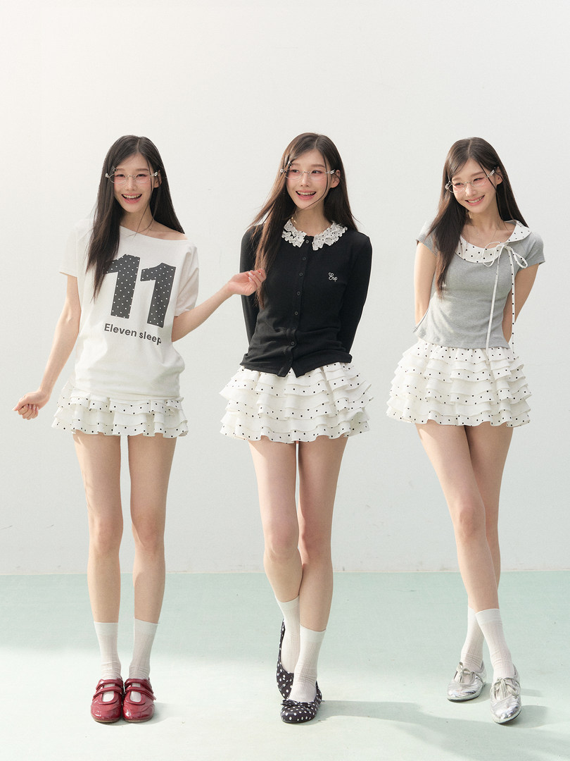 Three models wearing cute short-sleeve tops and layered ruffle skirts with socks and flats