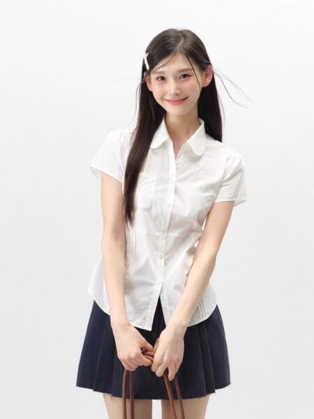 Woman wearing a white short-sleeve button-up blouse with a navy pleated skirt