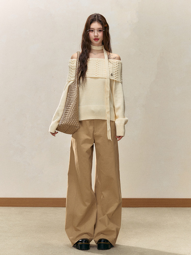 Model wearing a cream off-shoulder knit top with beige wide-leg pants and a woven tote bag