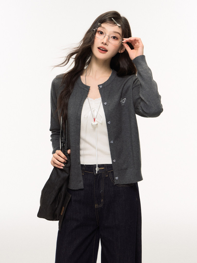 Female model wearing a dark gray cardigan over a white top with dark jeans and glasses