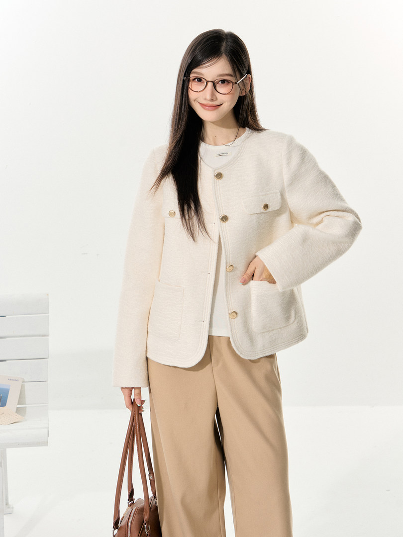 Model wearing a cream buttoned jacket with beige wide-leg pants and a brown handbag