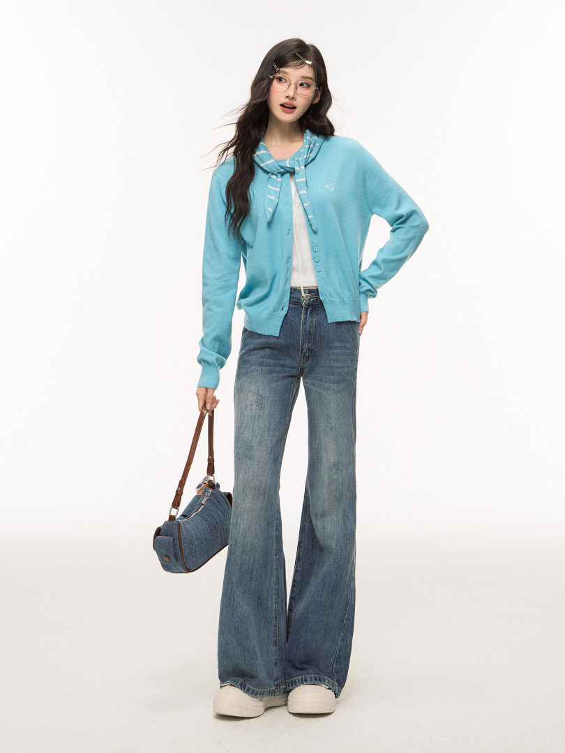 Model wearing a light blue cardigan with wide-leg jeans and a shoulder bag