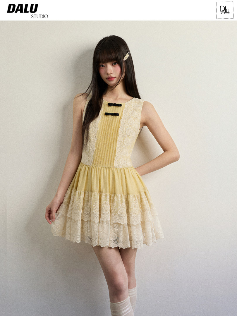 Model wearing a yellow lace sleeveless dress with tiered skirt