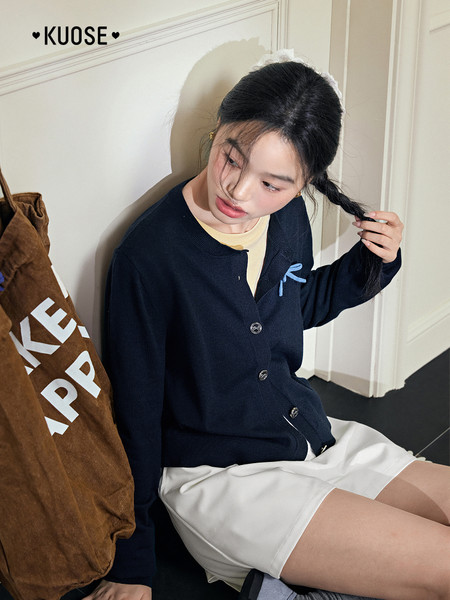 Model wearing a dark navy cardigan with a light top and white shorts