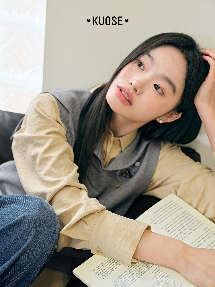 Model wearing a beige shirt layered under a gray vest