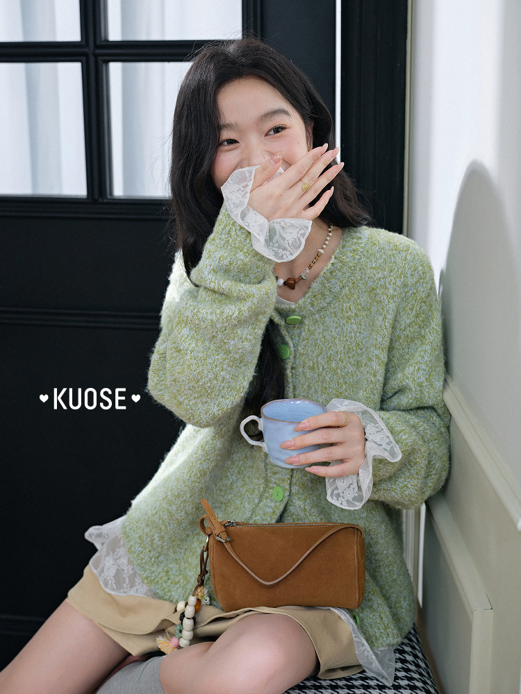 Model wearing a light green fuzzy cardigan with lace cuffs and a brown shoulder bag