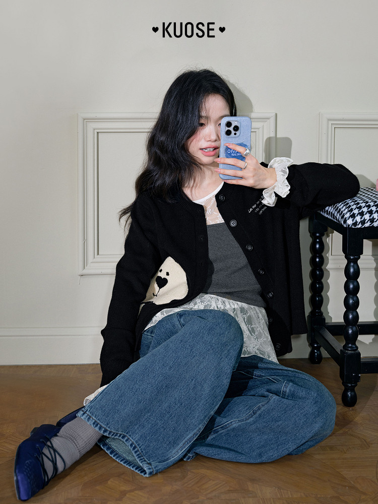 Black cardigan worn by a model with jeans and layered lace top