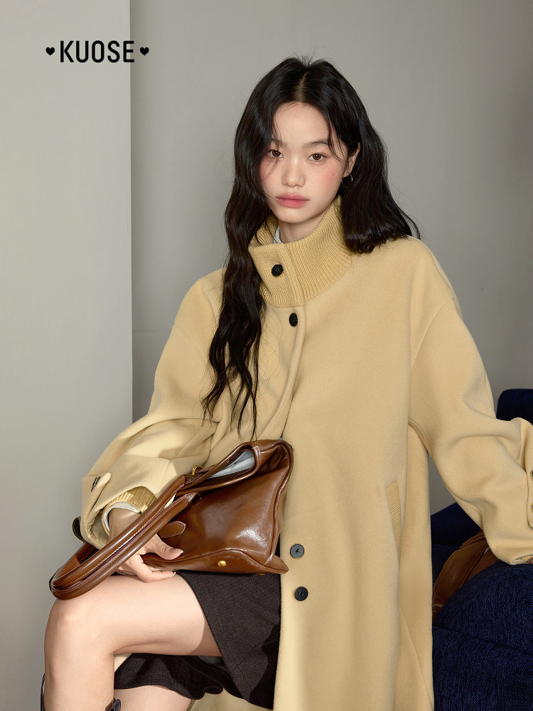 Model wearing a beige oversized coat with a brown handbag