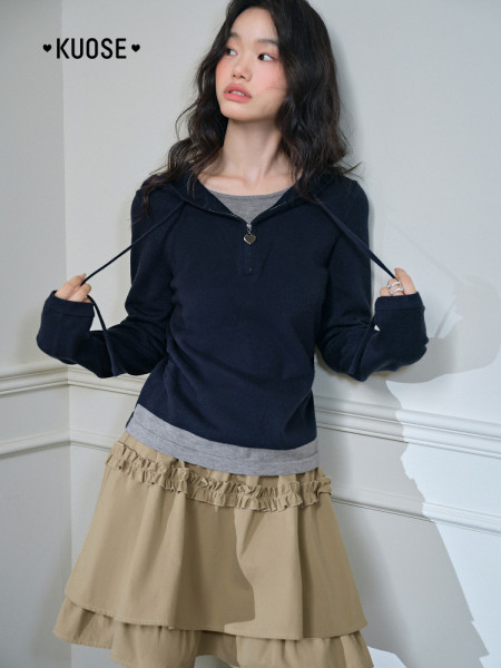 Model wearing a navy hooded long-sleeve top with a beige layered skirt
