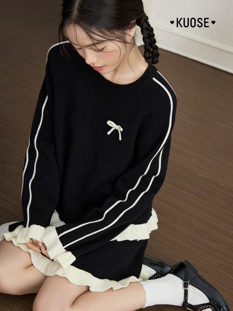 Black knit sweater dress with white stripes and ruffle trim worn by a model