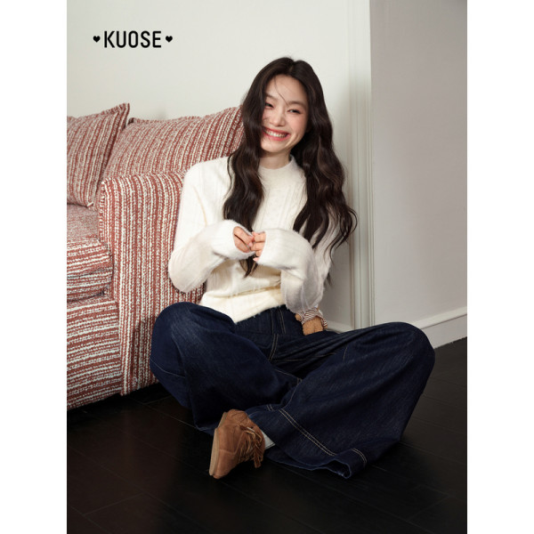 Model wearing a white sweater with dark wide-leg jeans indoors