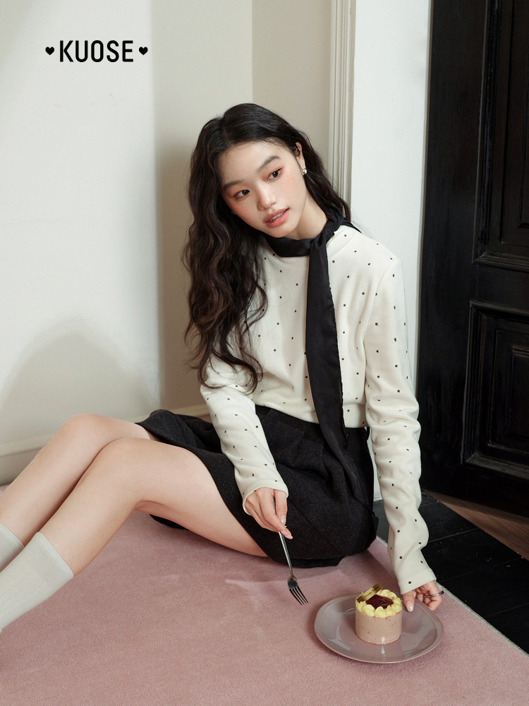 Female model wearing a cream polka dot blouse with black skirt and scarf