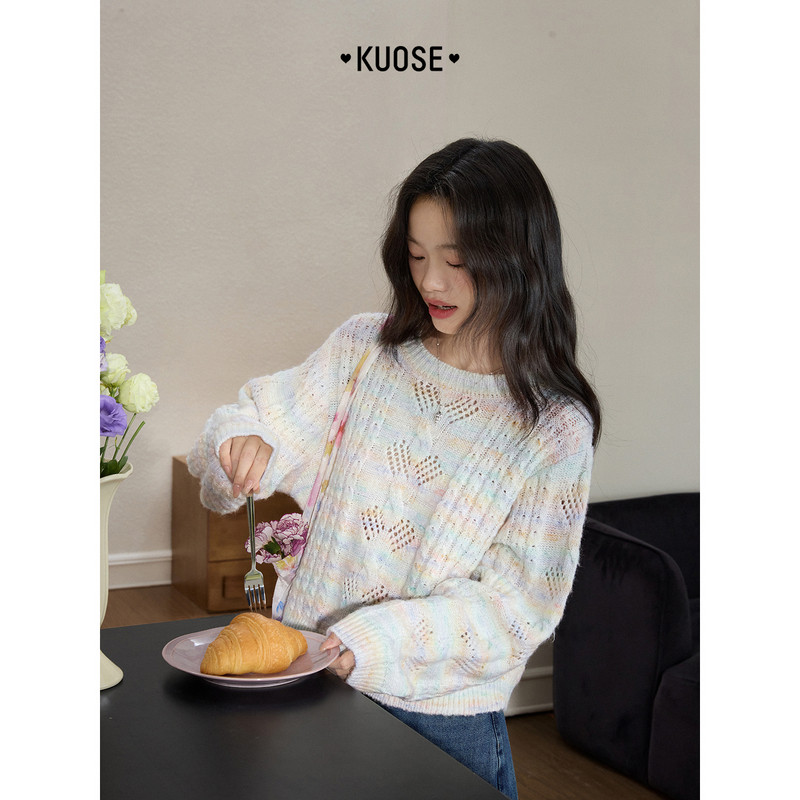 Model wearing a pastel knit sweater while holding a pastry