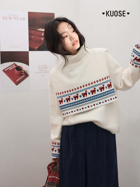 Model wearing a cream winter sweater with red and blue patterned details