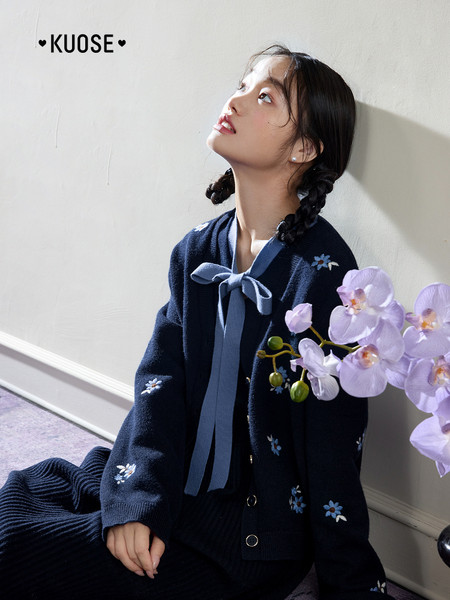 Navy knit cardigan worn by a model with bow tie and floral details