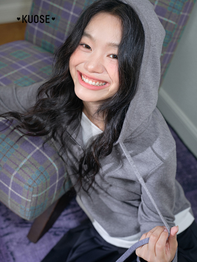 Woman wearing a gray hooded sweatshirt indoors