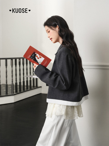 Model wearing a dark cropped jacket over a layered white outfit