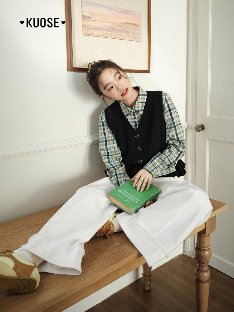 Model wearing a plaid shirt with a black vest and white wide-leg pants