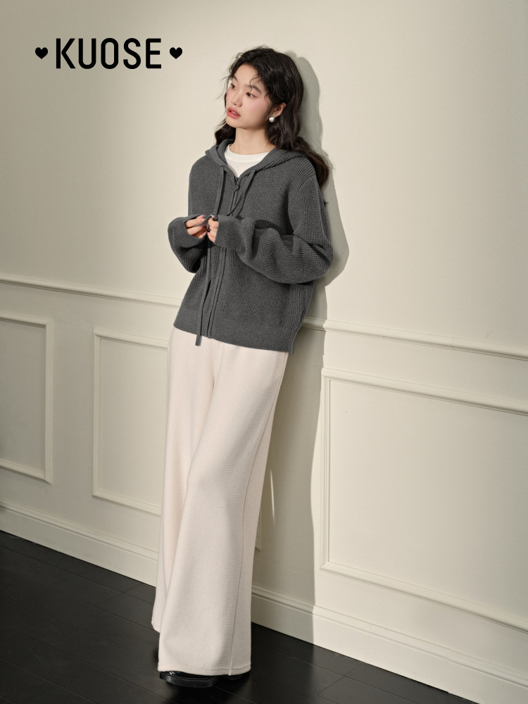 Model wearing a dark gray knit hoodie with wide cream pants