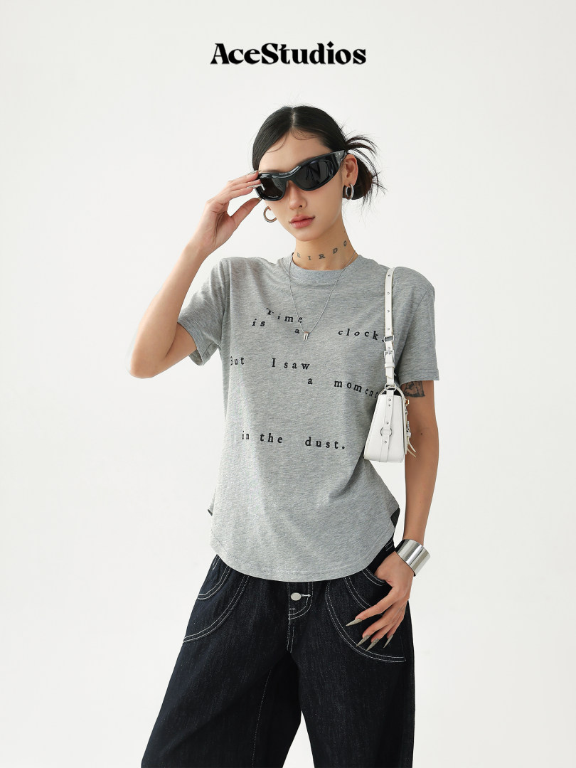 Model wearing a gray graphic T-shirt with black pants and sunglasses
