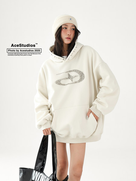 Model wearing an oversized cream hoodie sweatshirt with studded hood detail