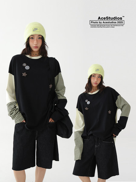 Model wearing a black oversized long-sleeve top with striped sleeves, shorts, and a neon beanie
