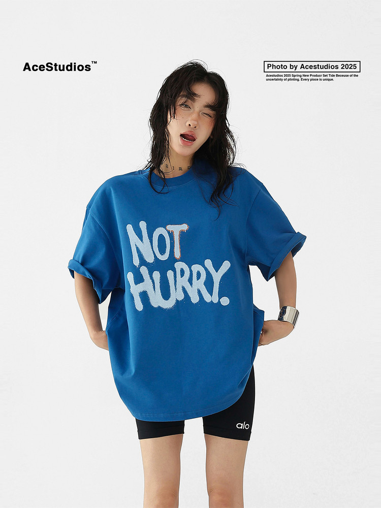 Blue oversized graphic T-shirt worn by a model with 'NOT HURRY.' print