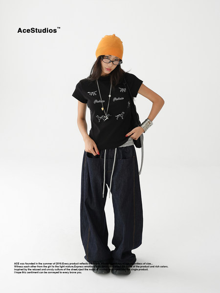 Model wearing a black graphic t-shirt, baggy dark jeans, and an orange beanie