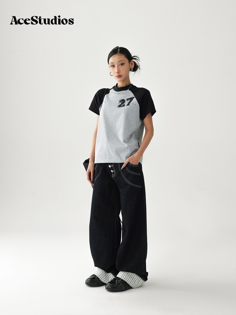 Model wearing a black-and-gray raglan graphic T-shirt with wide-leg black jeans