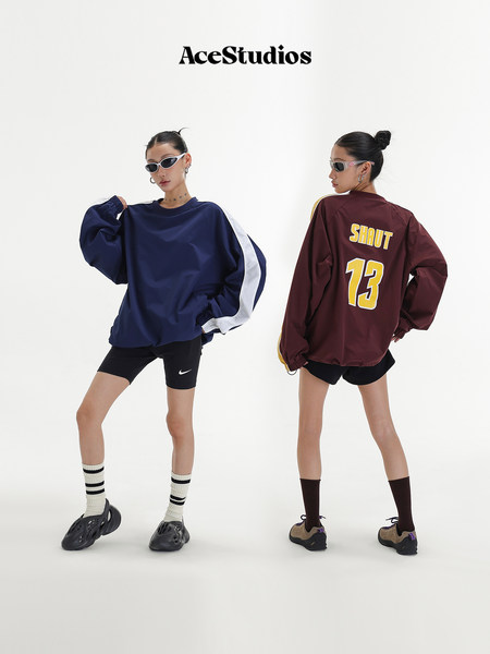 Two models wearing oversized sporty long-sleeve tops in navy and burgundy