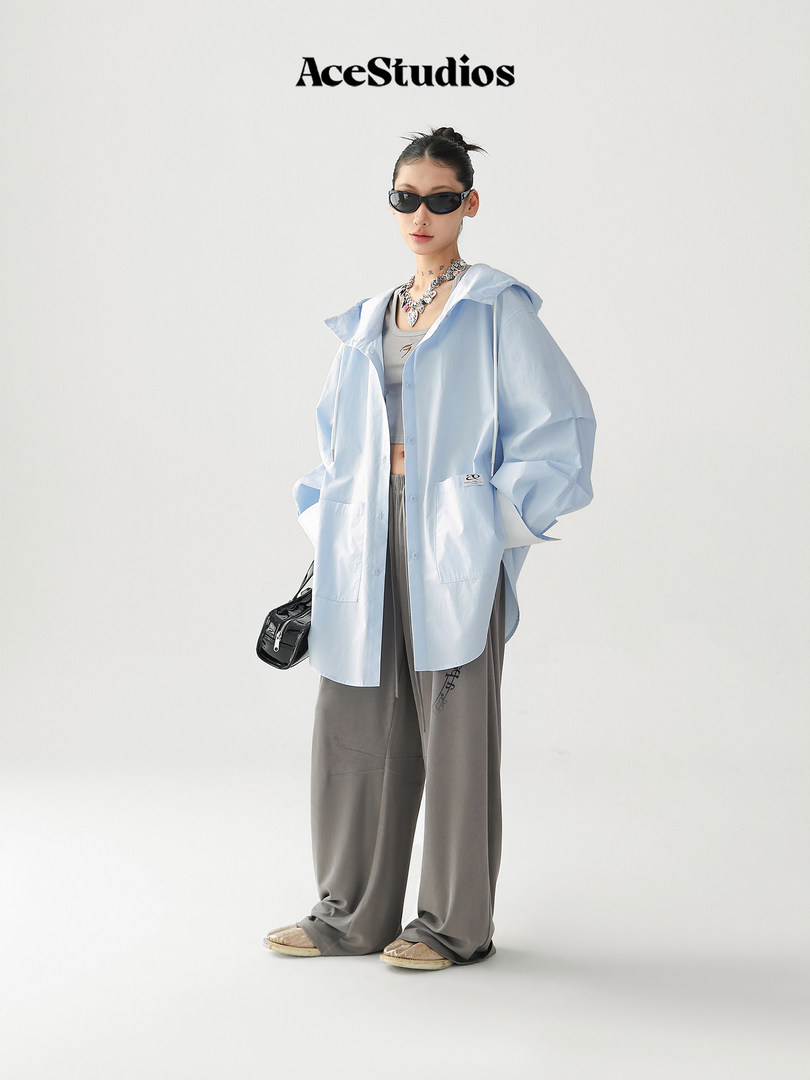 Model wearing a light blue oversized hooded shirt jacket with wide gray pants
