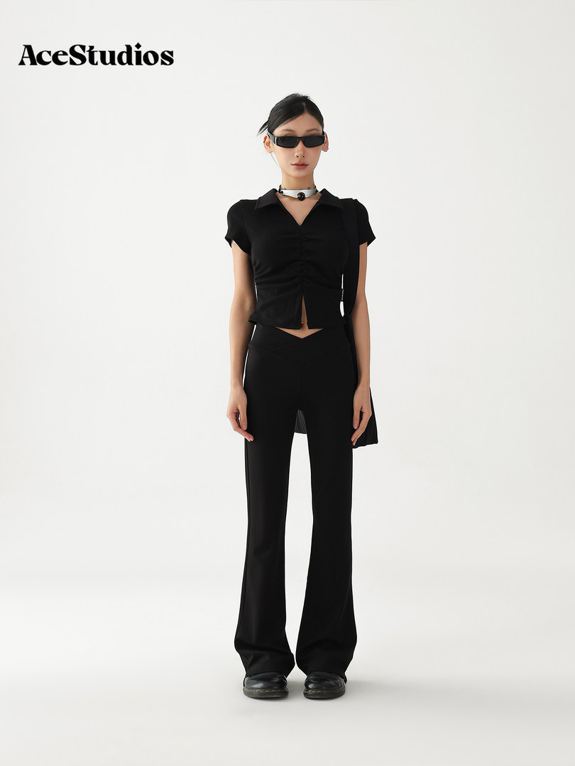 Model wearing a black fitted collared top with flared pants and sunglasses