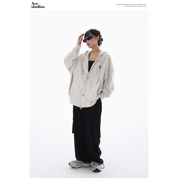 Model wearing an oversized light gray hoodie with black wide-leg pants and sneakers